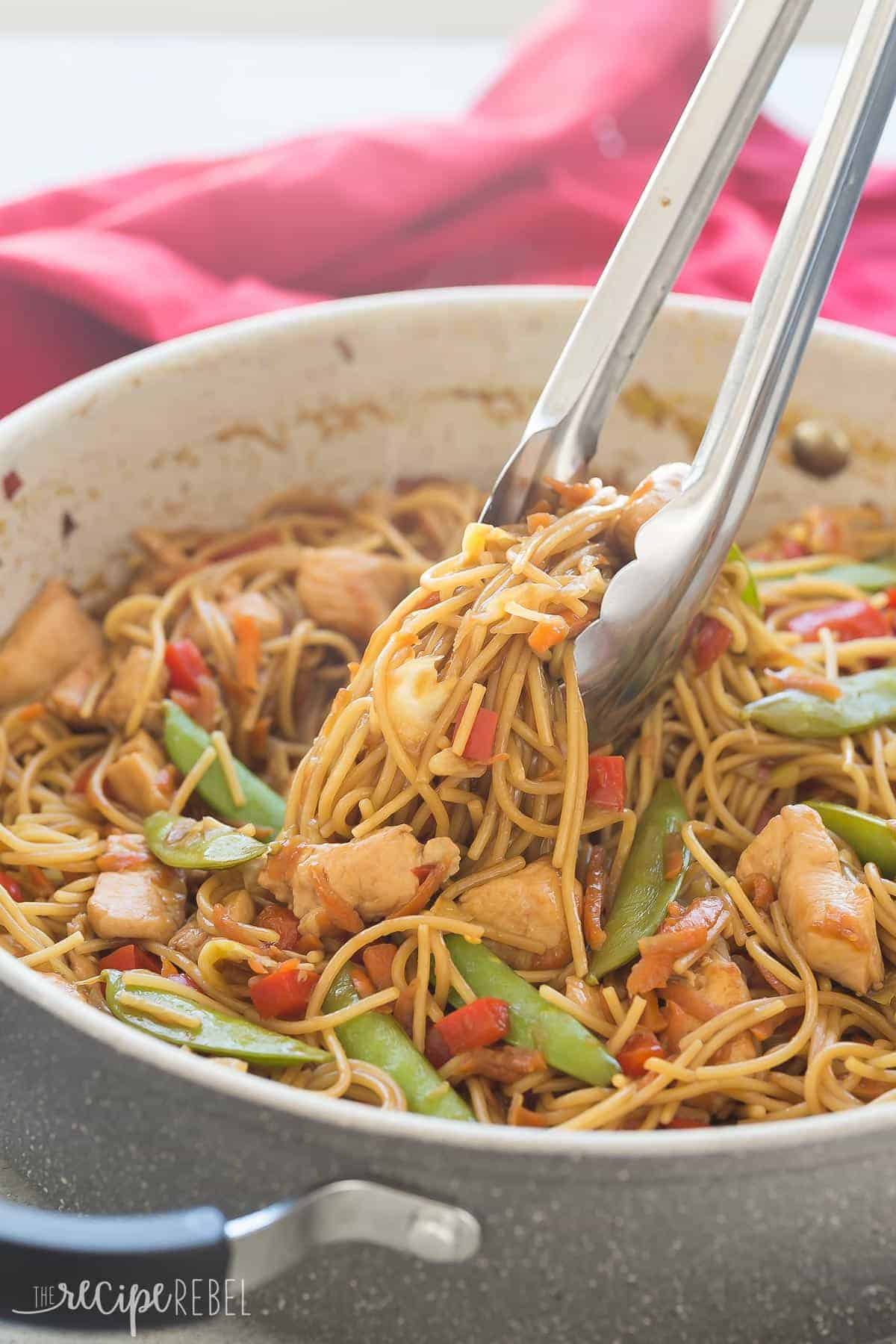 one pot chicken chow mein in grey pan with metal tongs pulling some noodles up
