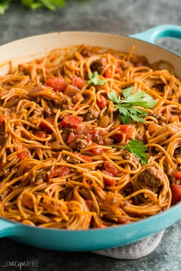 one pot spaghetti in blue le creuset braiser with fresh parsley on top