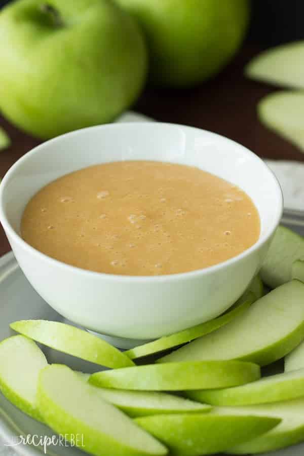 caramallow fruit dip in a white bowl with sliced green apples all around