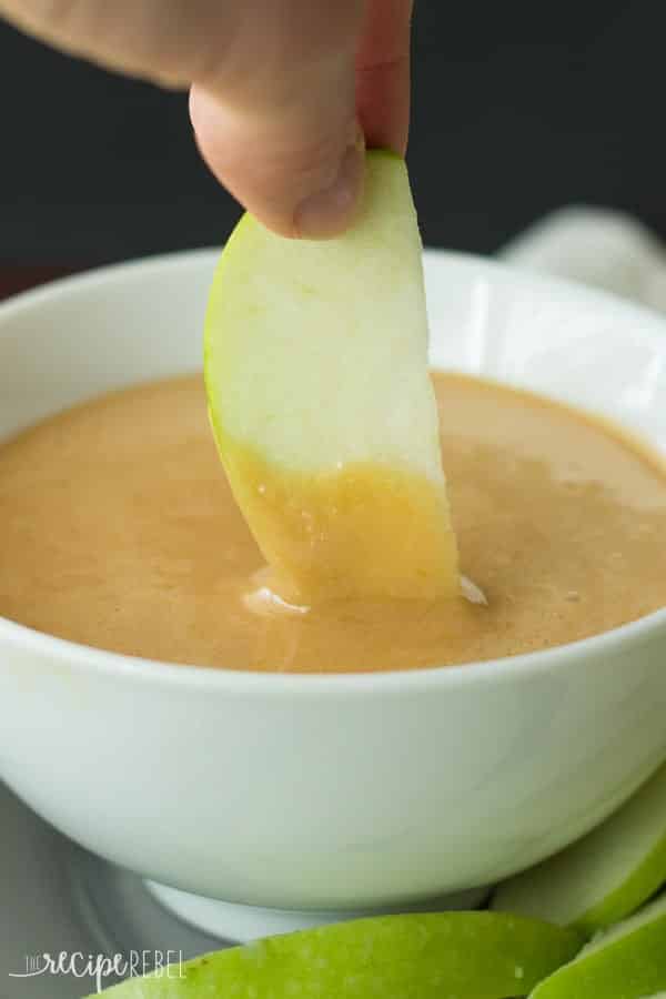 green apple slice being dipped into caramallow dip