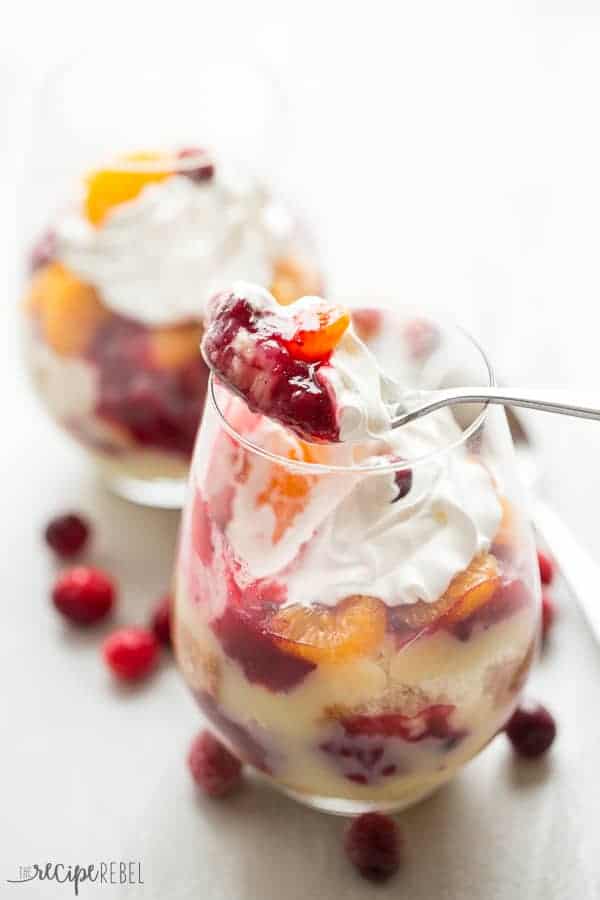 glass of cranberry orange trifle with spoon taking scoop out of glass