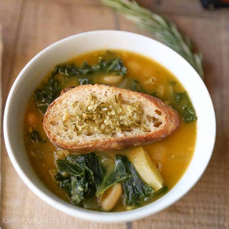 potato white bean kale soup with crusty bread on top in soup