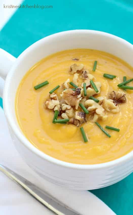 butternut squash soup in white bowl topped with walnuts and chives