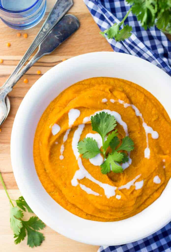 curried sweet potato lentil soup overhead in white bowl with cream swirl