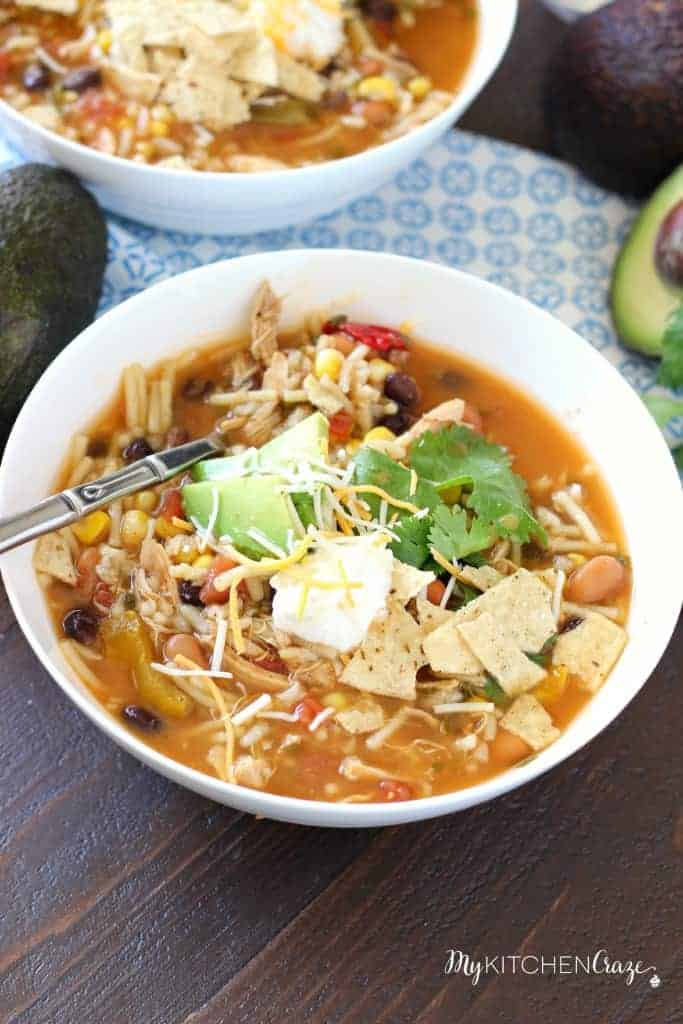 taco soup in white bowl topped with sour cream cheese and avocado