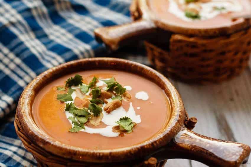 slow cooker thai pumpkin soup in brown bowls with blue plaid napkin behind