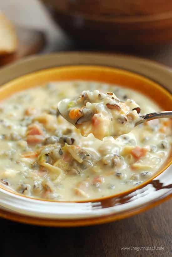 creamy chicken wild rice soup in brown bowl with spoon scooping bite