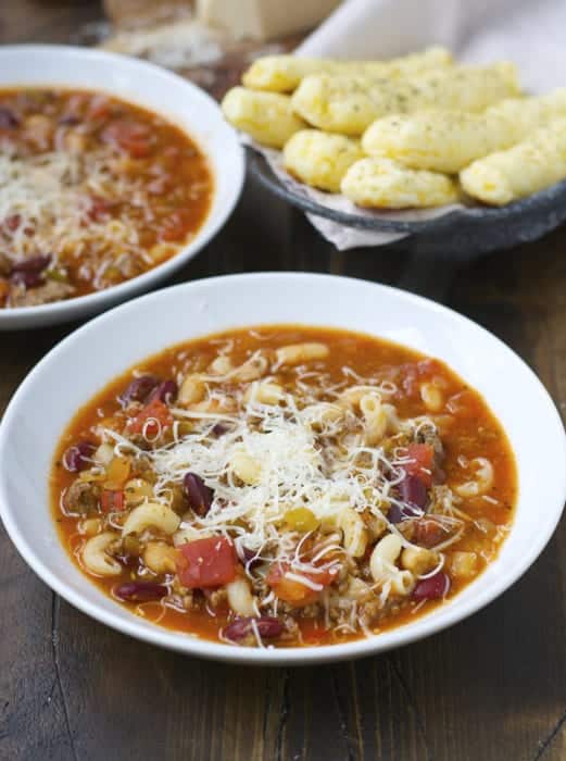 slow cooker pasta fagioli in white bowl topped with shredded parmesan