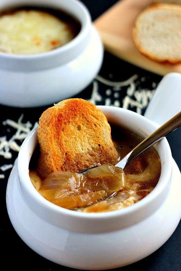 french onion soup in white bowl with crusty bread in the side