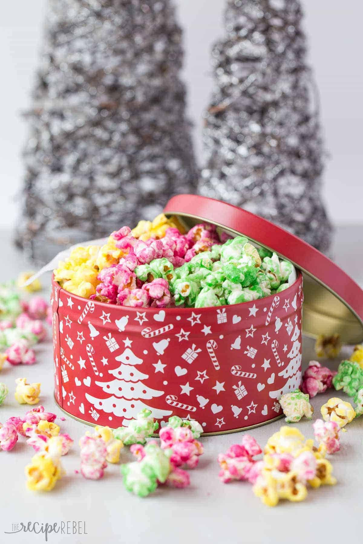 red christmas tin with yellow pink and green candy popcorn and sparkly christmas trees behind
