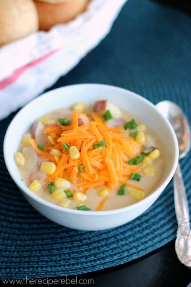 creamy nacho potato soup in white bowl topped with cheddar cheese corn and green onions