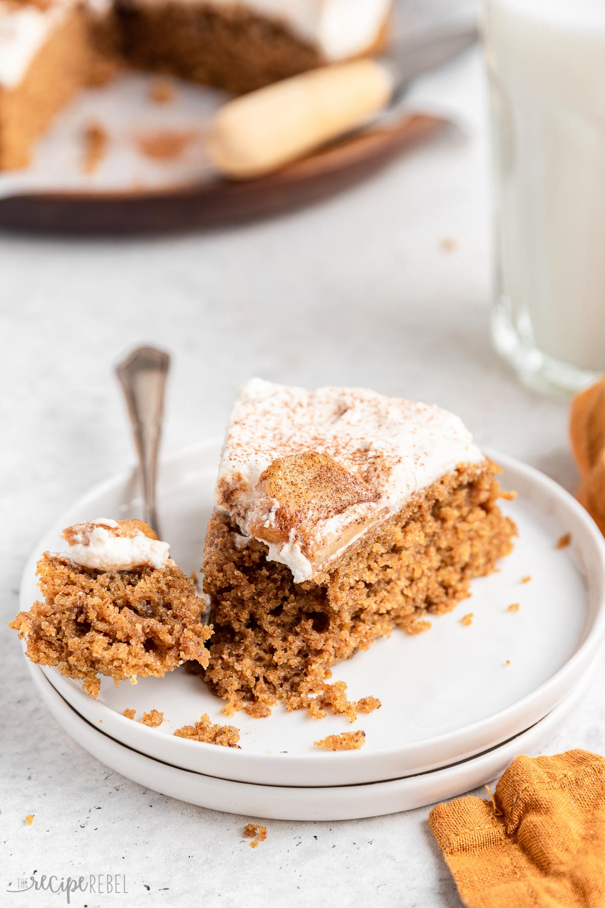 fork taking a bite of apple spice cake on plate.