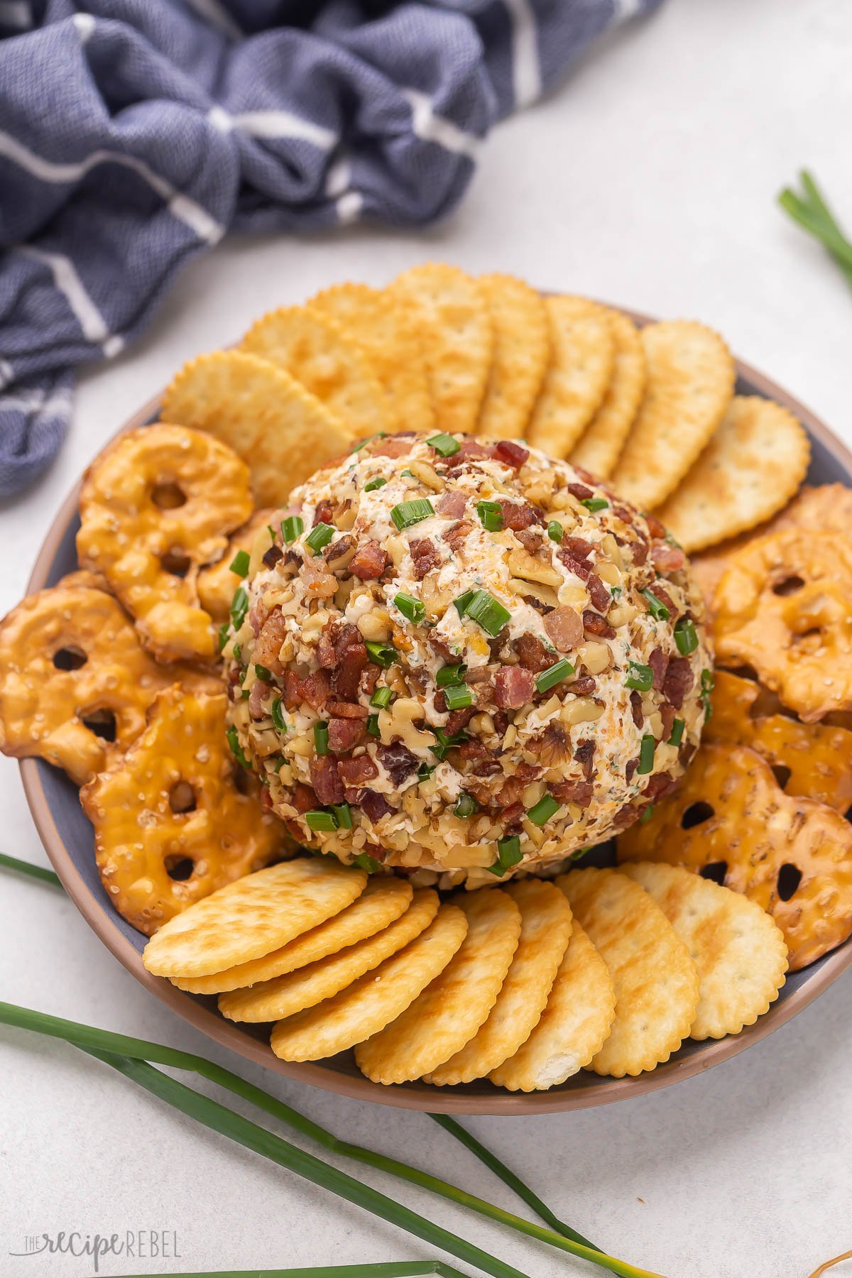 whole bacon cheese ball on plate with crackers and pretzels.