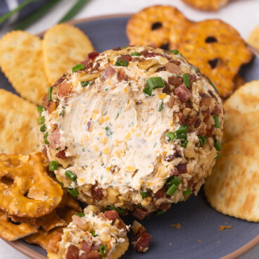 cheese ball on a blue plate with some scooped onto a cracker.