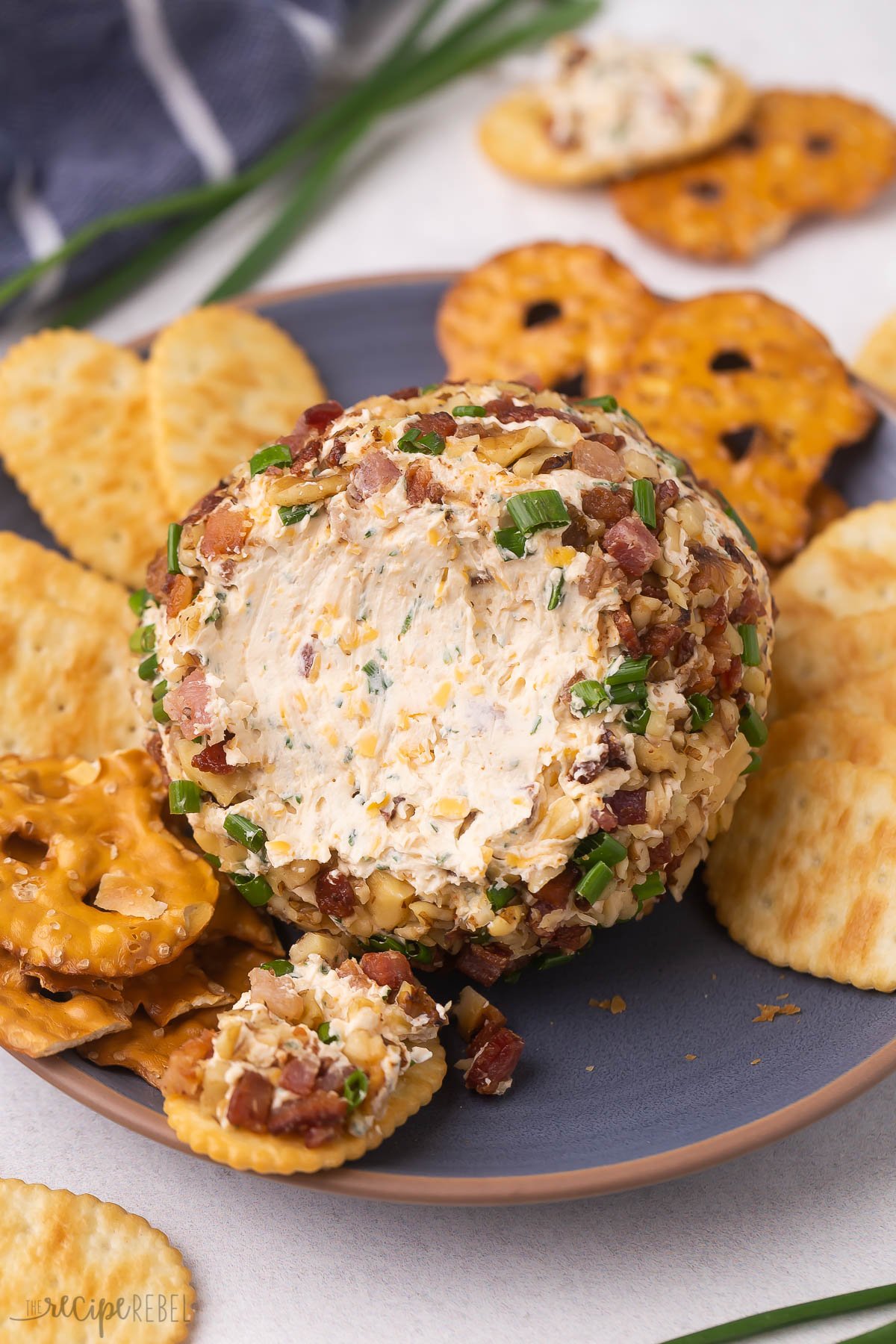 cheese ball on a blue plate with some scooped onto a cracker.