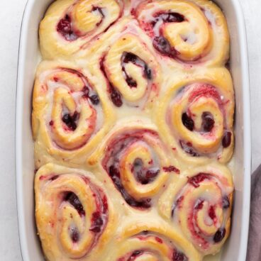 overhead image of pan of cranberry sweet rolls with white chocolate glaze.