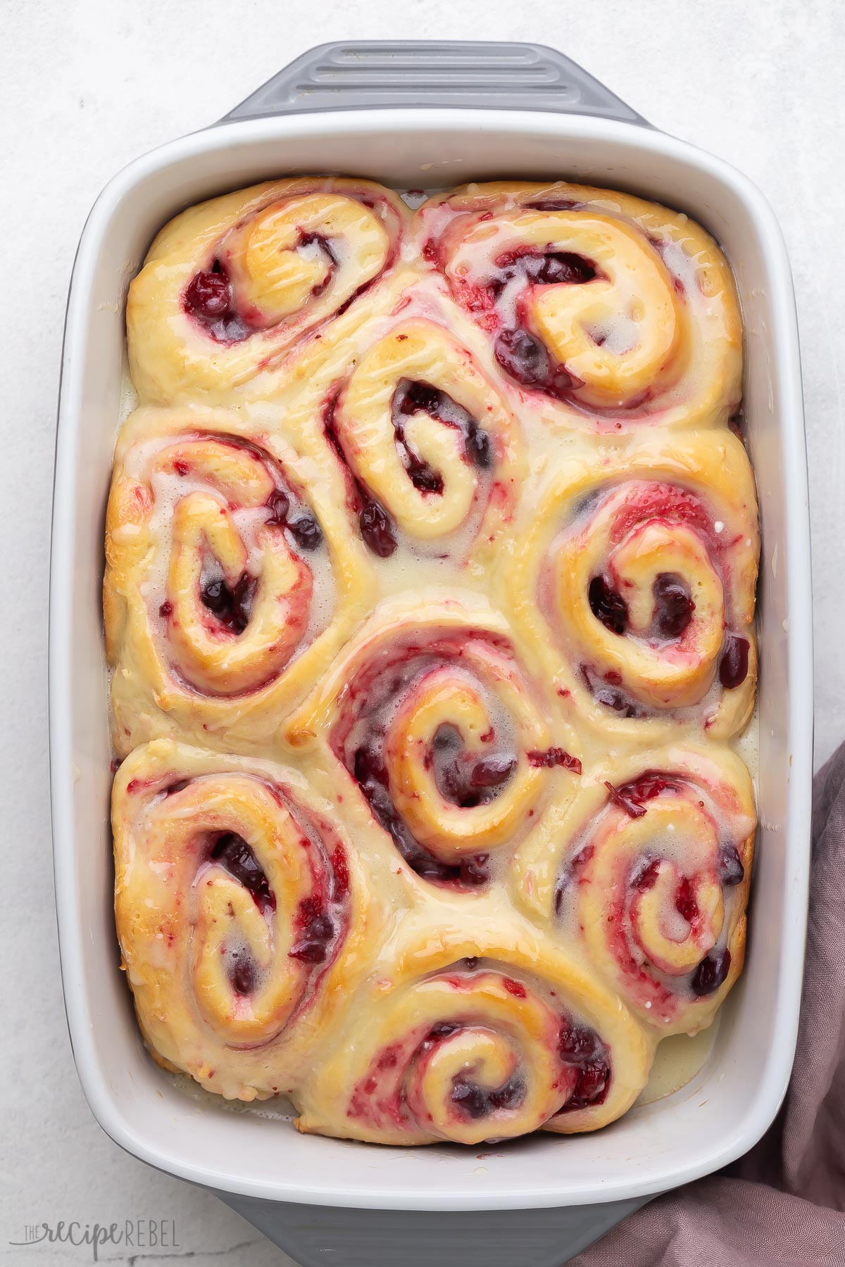 overhead image of pan of cranberry sweet rolls with white chocolate glaze.