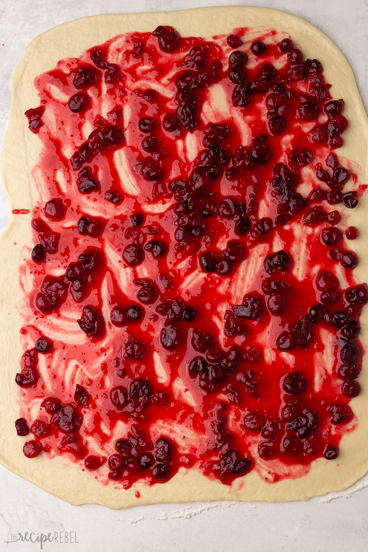 cranberry sauce spread on yeast dough ready to roll.