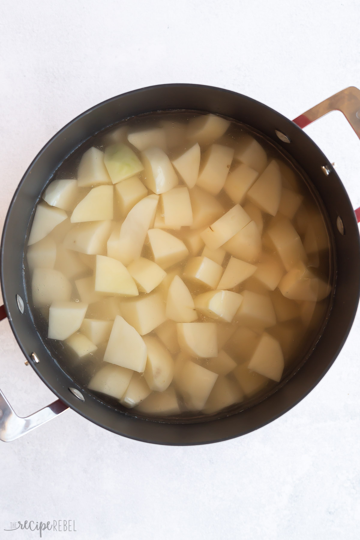 cubed potatoes in black pot of boiling water.