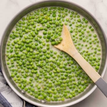 square image of creamed peas in a stainless steel pan.
