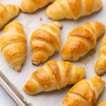 multiple crescent rolls on a baking sheet with parchment paper.