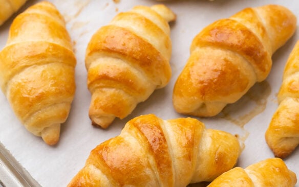 multiple crescent rolls on a baking sheet with parchment paper.