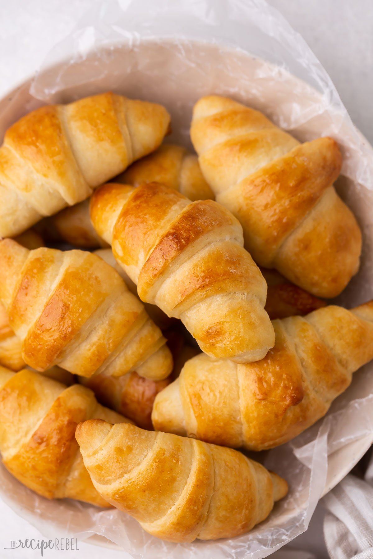 close up overhead image of crescent rolls in a bowl with parchment paper.