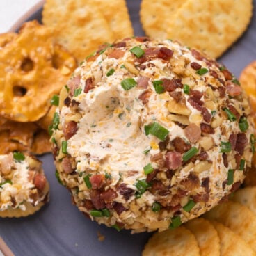 close up image of cheese ball with some scooped out on a cracker.