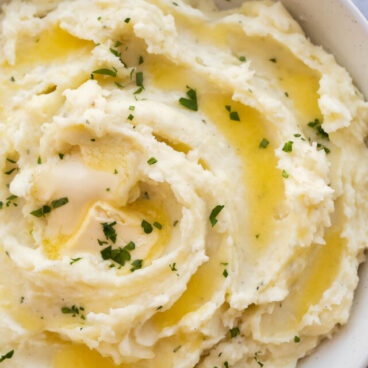 close up image of cream cheese mashed potatoes with melted butter.