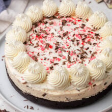 close up image of no bake peppermint bark cheesecake with whipped cream crushed candy canes and chocolate shavings.