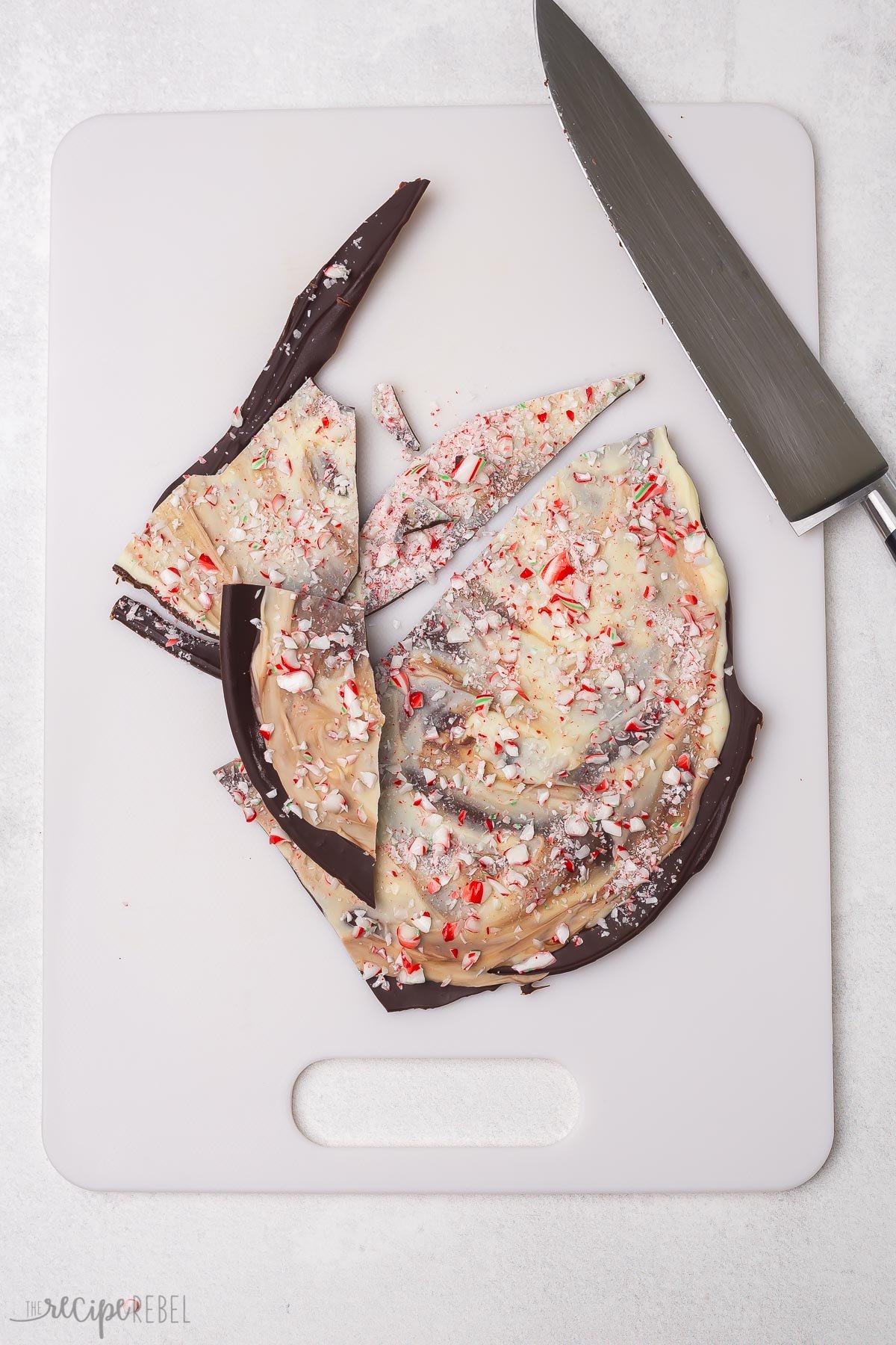 peppermint bark on white cutting board with knife.