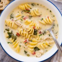 close up image of white bowl with italian chicken noodle soup and spoon.