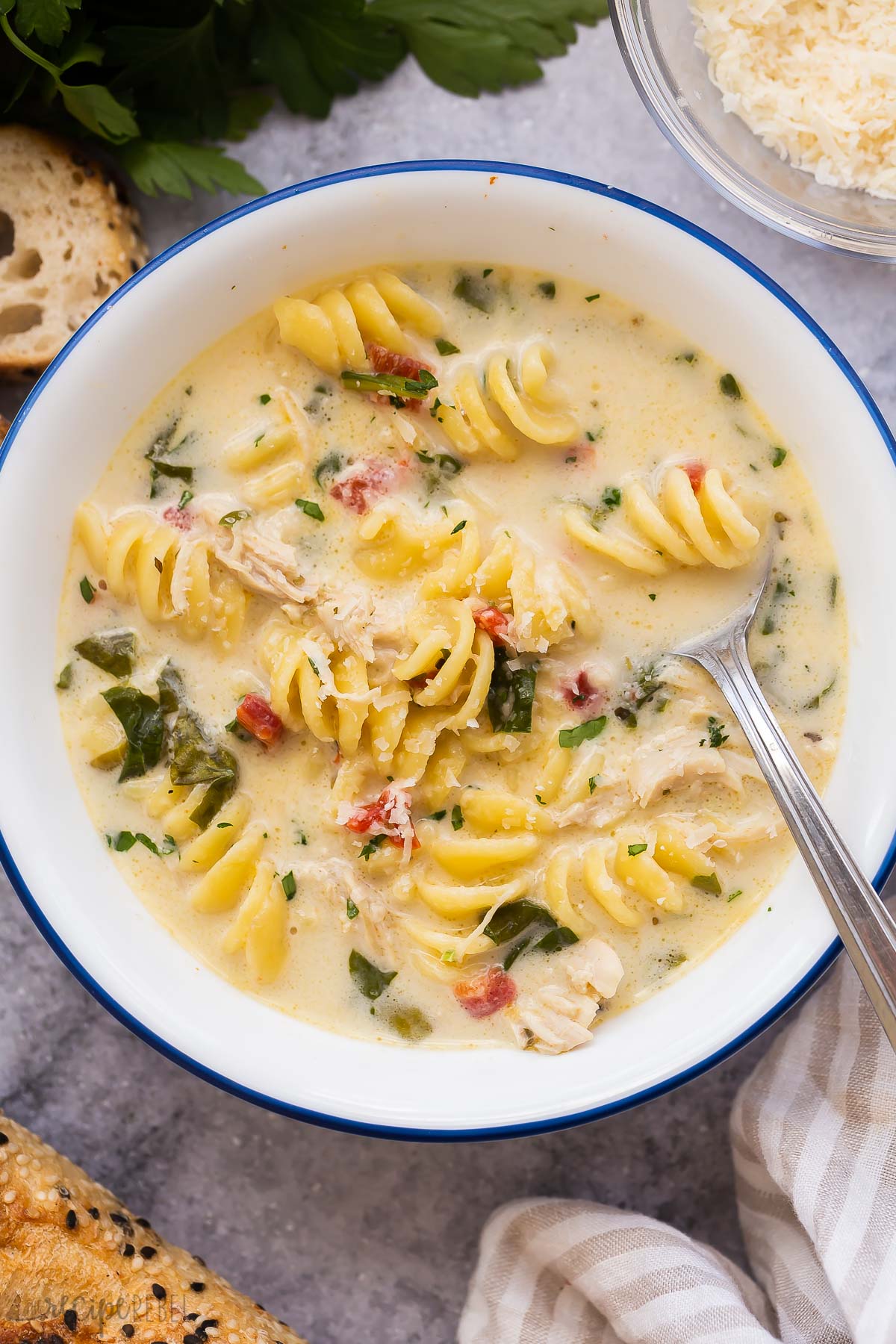 close up image of white bowl with italian chicken noodle soup and spoon.