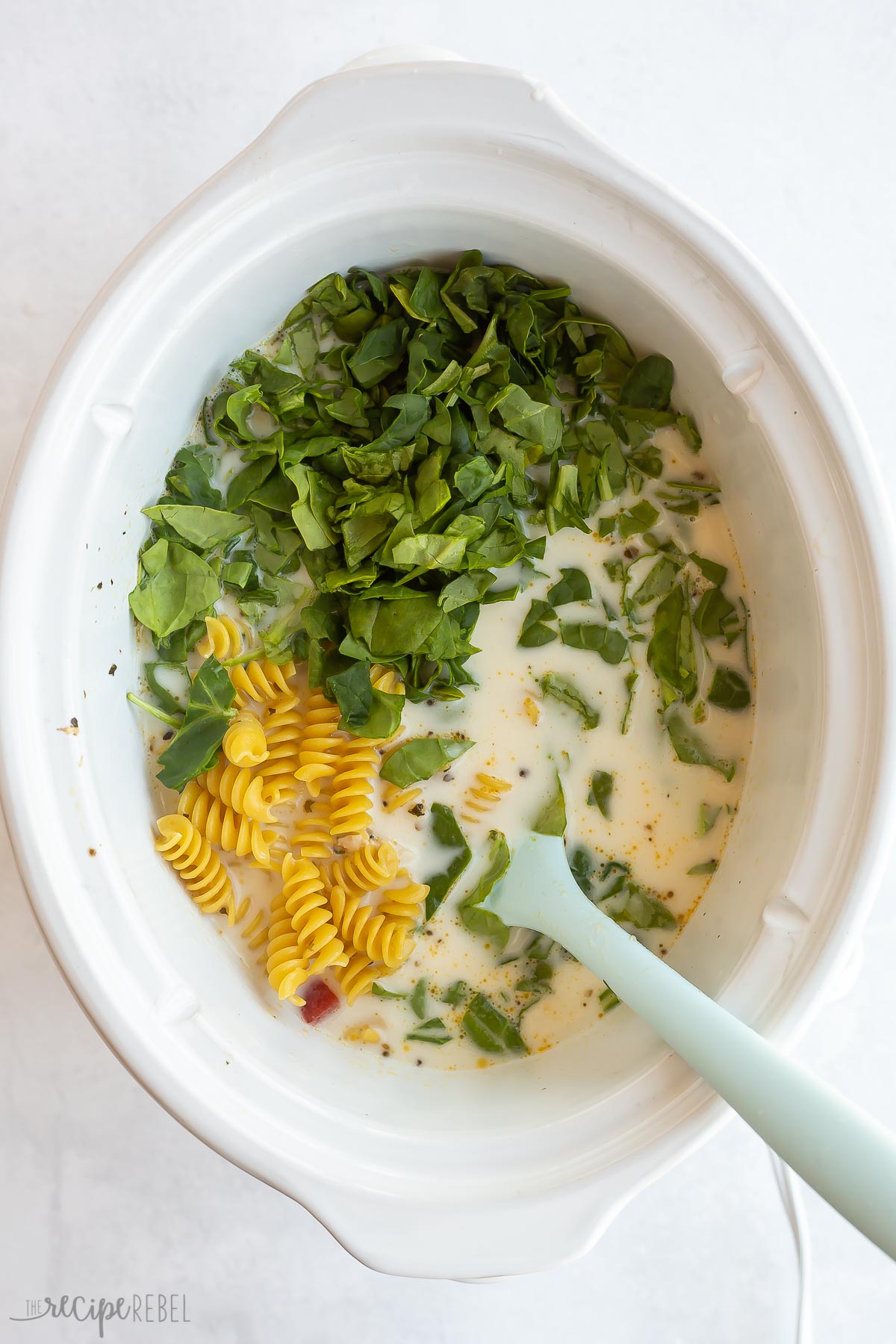 dry pasta and spinach added to soup in crockpot.