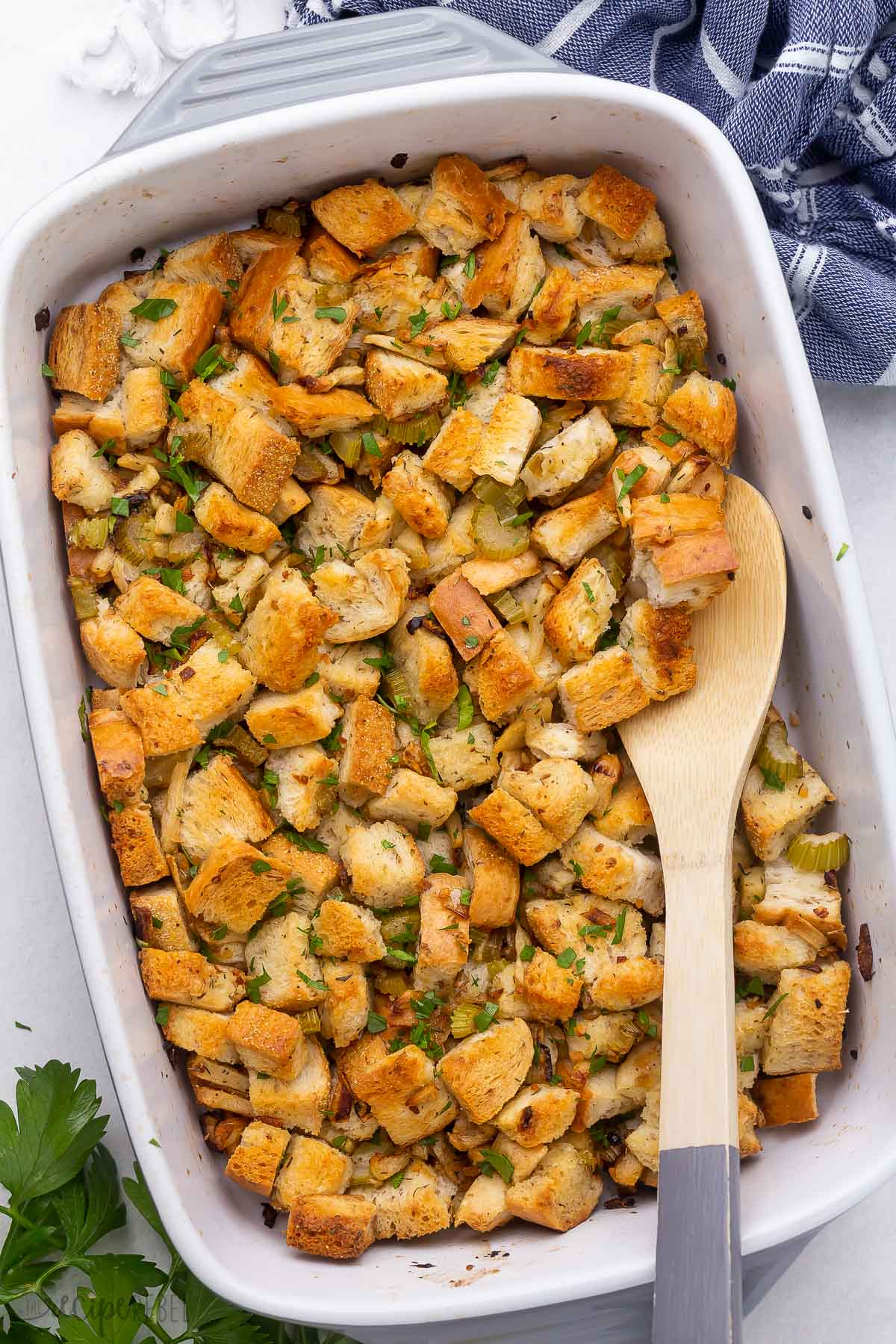 overhead image of stuffing in white backing dish with wooden spoon.