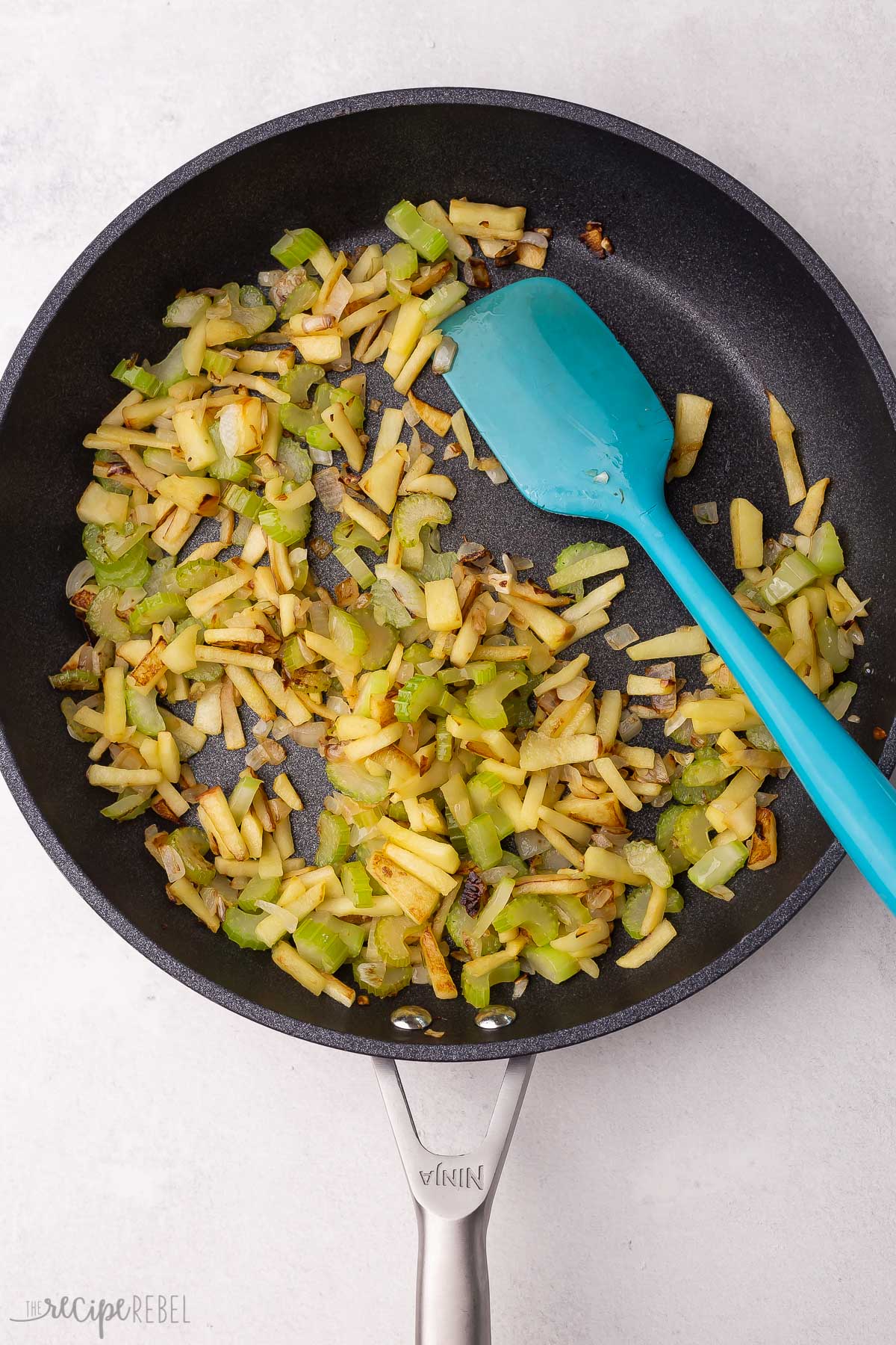 celery onion and apple sauteeing in black skillet.