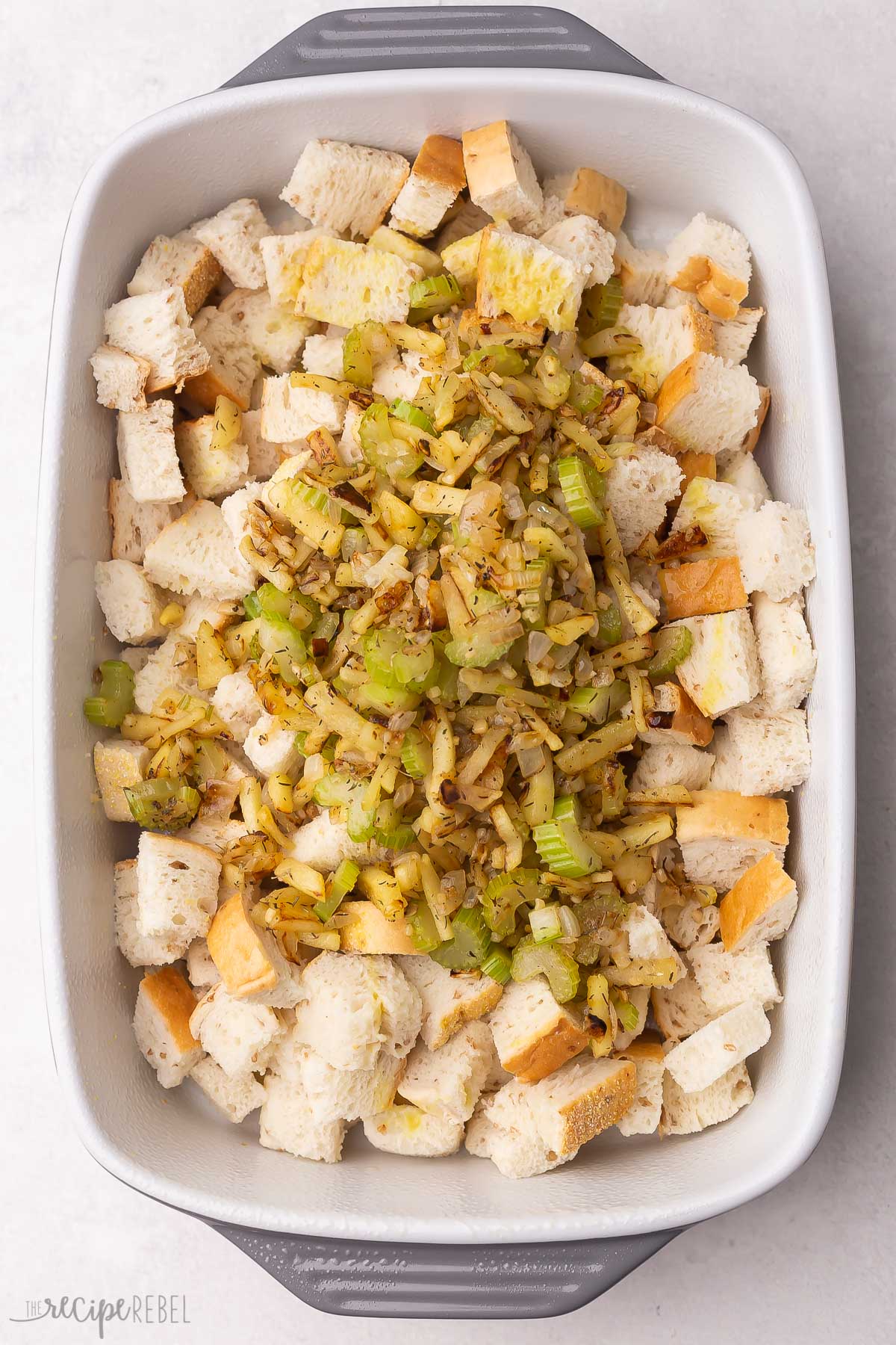 sauteed vegetables added to bread cubes in baking dish.