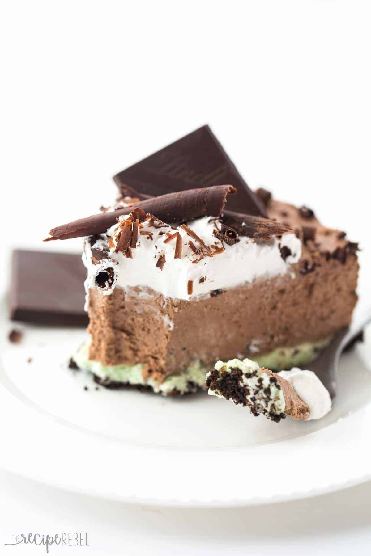 piece of no bake mint chocolate cheesecake on white plate with bite out and topped with whipped cream