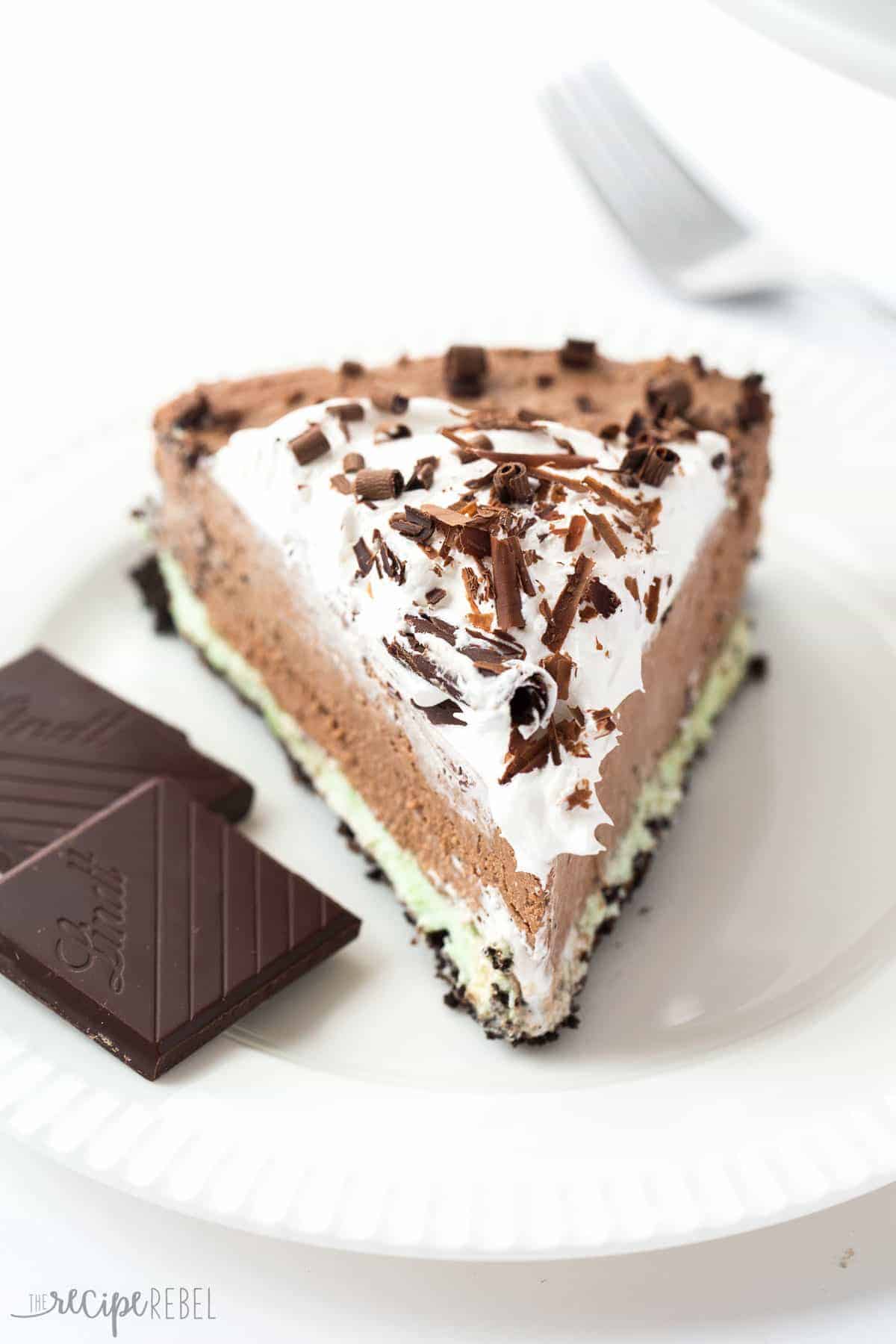 slice of mint chocolate no bake cheesecake on white plate with whipped cream and chocolate shavings
