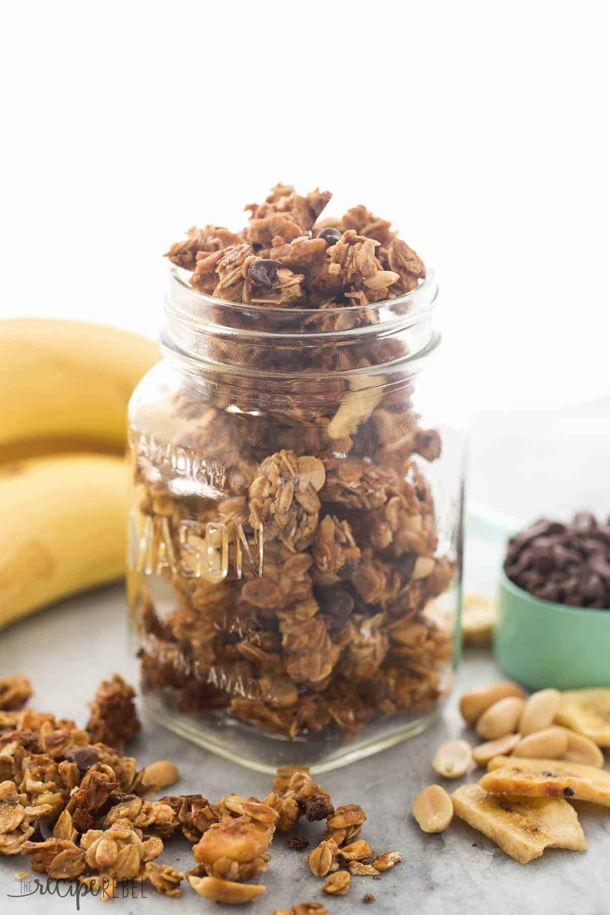 chocolate peanut butter granola in glass mason jar with bananas in the background