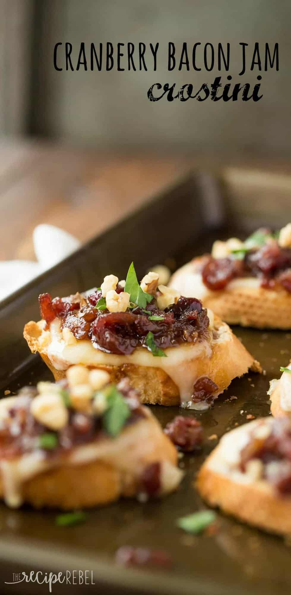 cranberry bacon jam crostini on a sliced baguette with walnuts and parsley lined up on a sheet pan