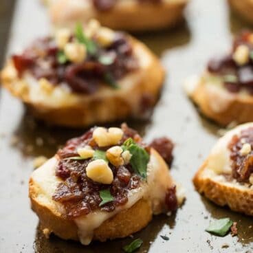 Easy, make ahead Cranberry Bacon Jam and cheese on top of a crusty baguette, topped with chopped walnuts for extra crunch -- these crostini are the perfect combination of sweet, smoky, salty and cheesy!