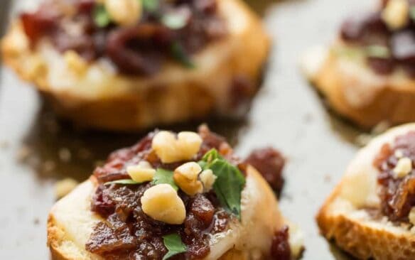 Easy, make ahead Cranberry Bacon Jam and cheese on top of a crusty baguette, topped with chopped walnuts for extra crunch -- these crostini are the perfect combination of sweet, smoky, salty and cheesy!