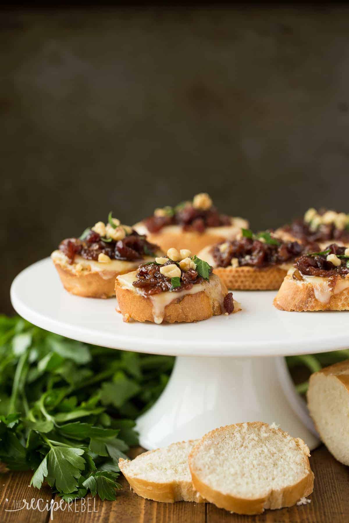 white cake plate with cranberry bacon jam crostini on op and fresh parsley on the side