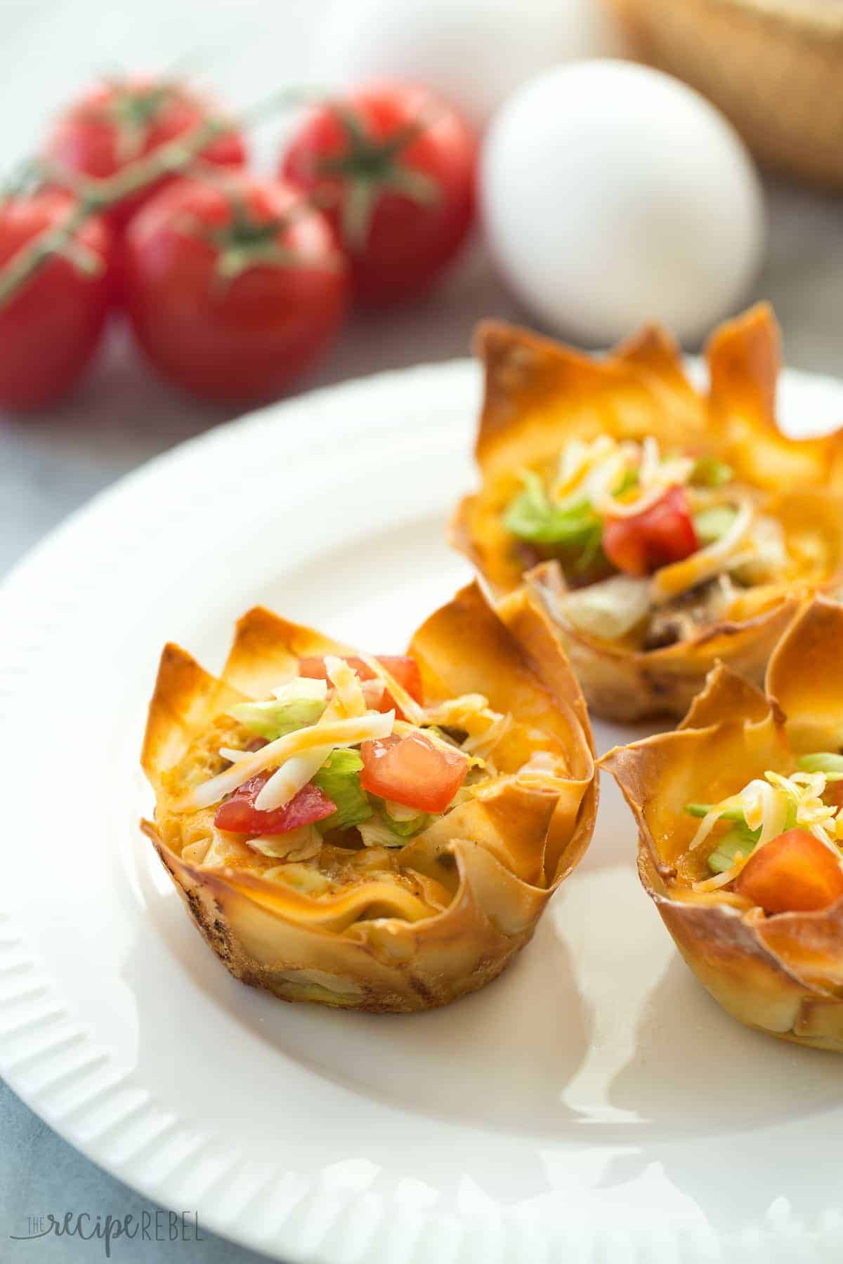 close up of mini mexican wonton quiche topped with lettuce tomato and cheese