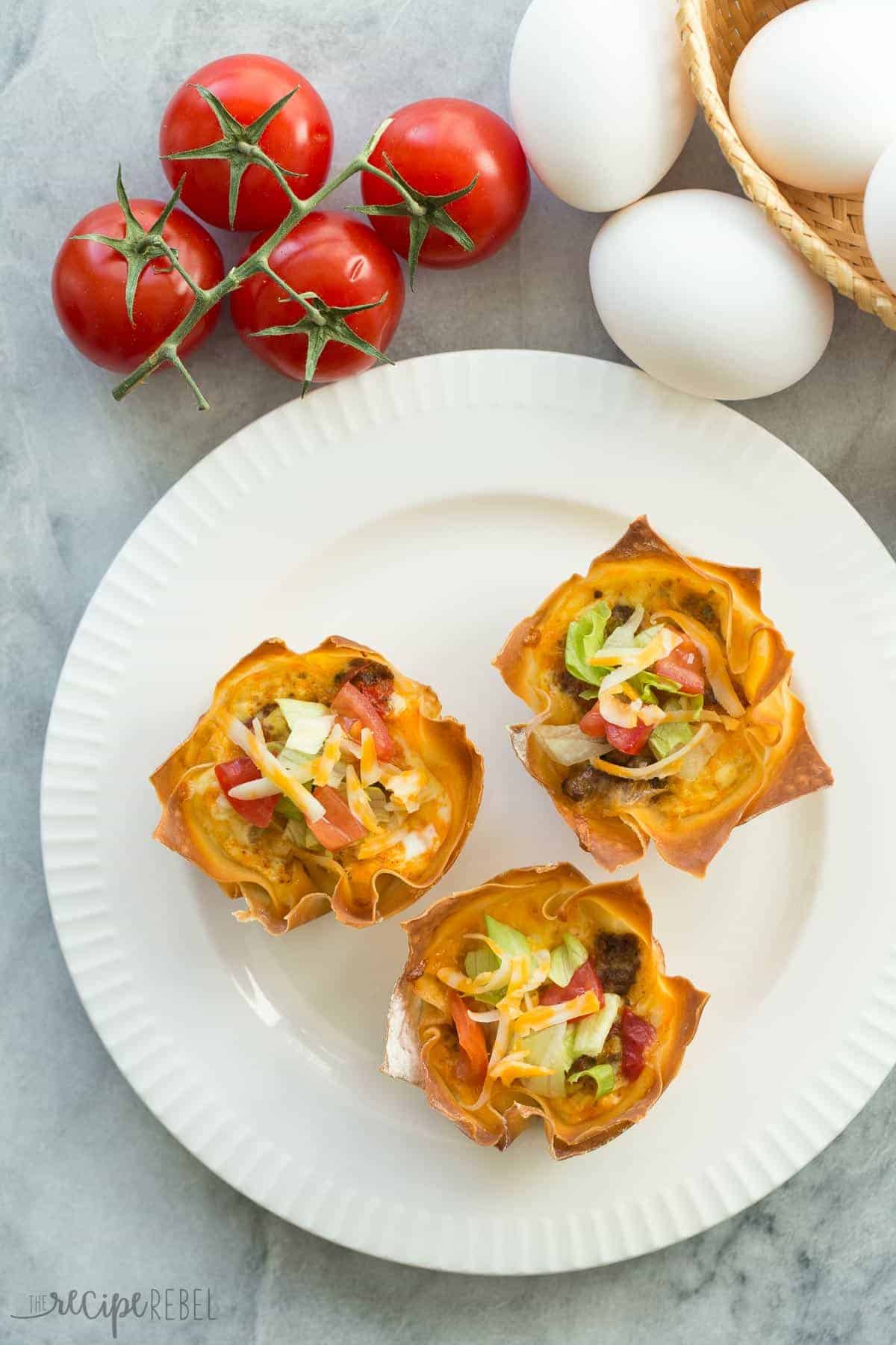 overhead image of three mini mexican wonton quiche topped with lettuce tomato and cheese