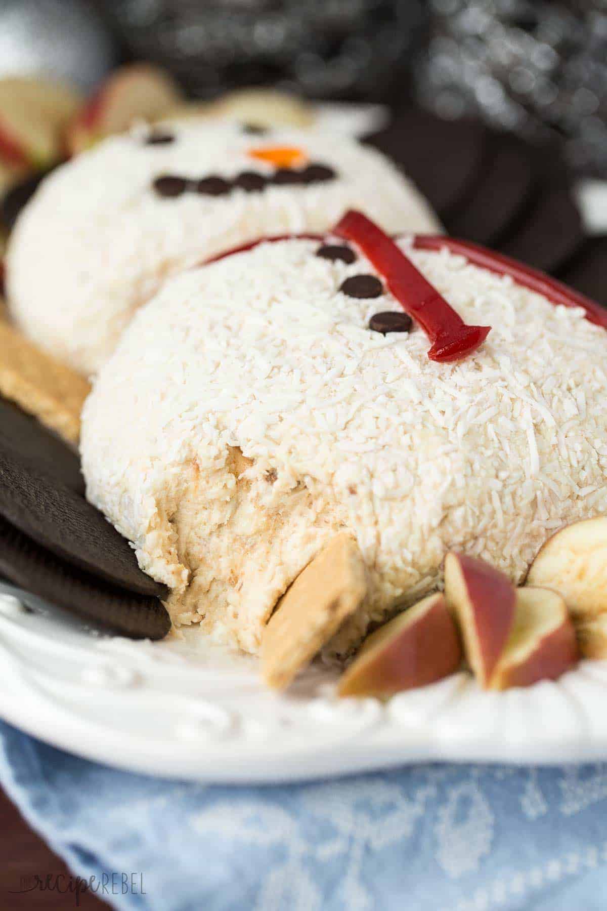 white chocolate snowman cheeseball with graham cracker taking a scoop off the side