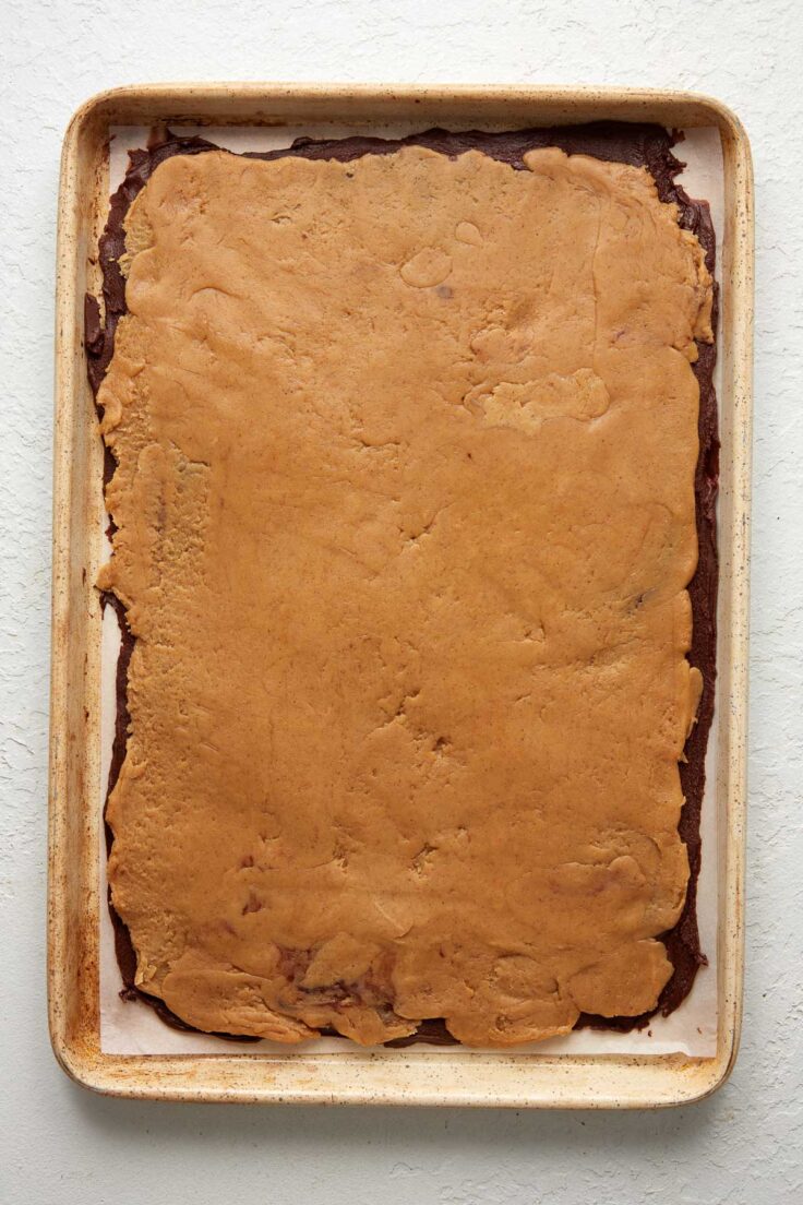 peanut butter fudge spread over chocolate fudge on baking sheet.