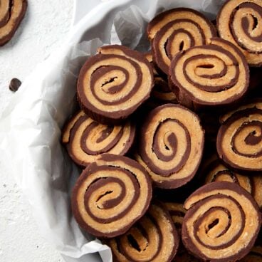 slices of pinwheel fudge in a bowl with parchment.