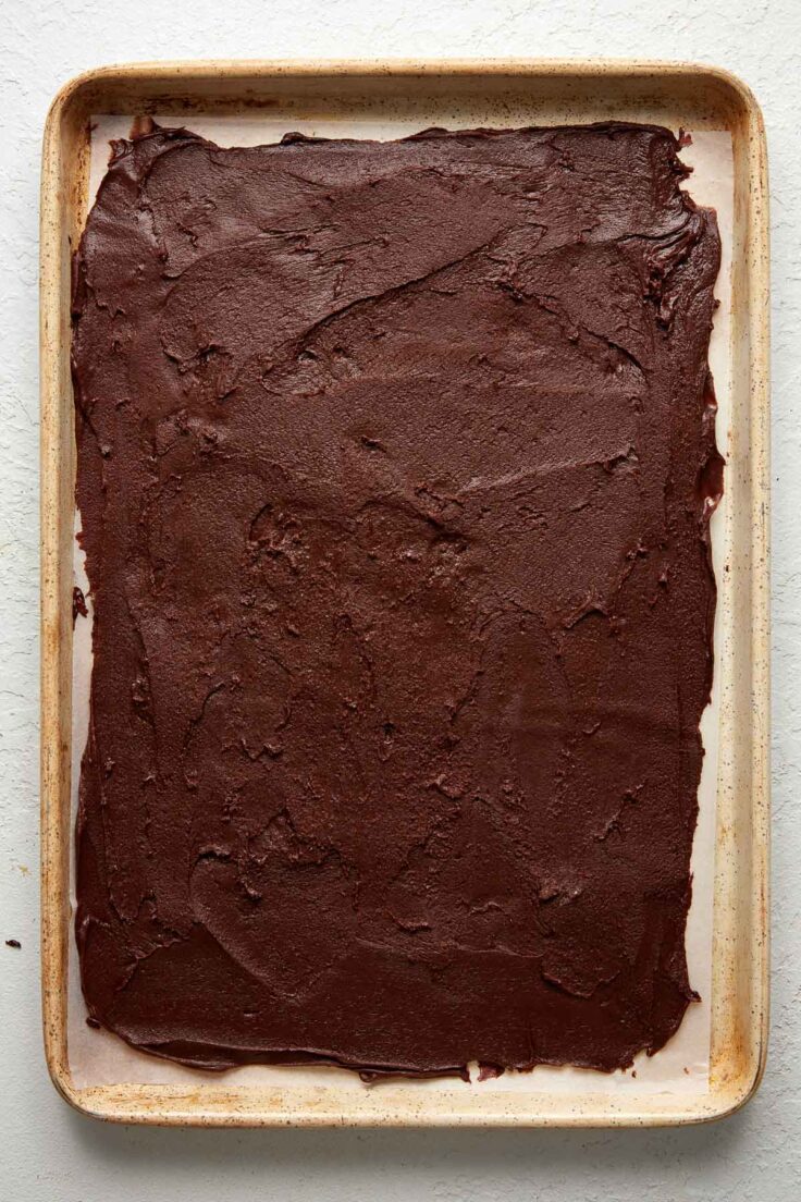 chocolate fudge spread out on parchment on a baking sheet.